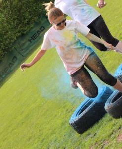 Woman running through a tyre on colour run