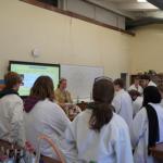 Students in lab coats watching a teacher do science experiments