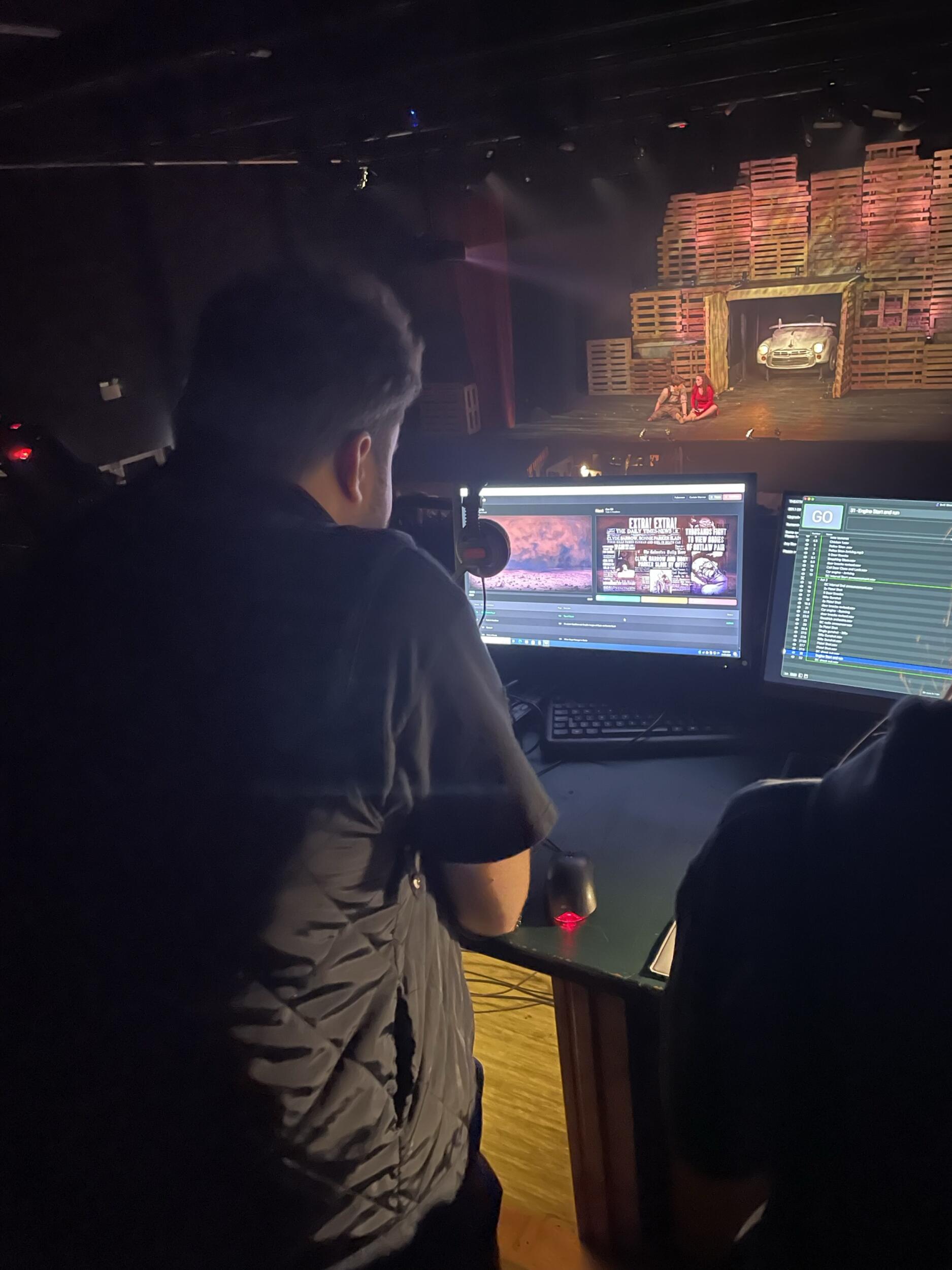 Student at sound and light desk looking at students on stage