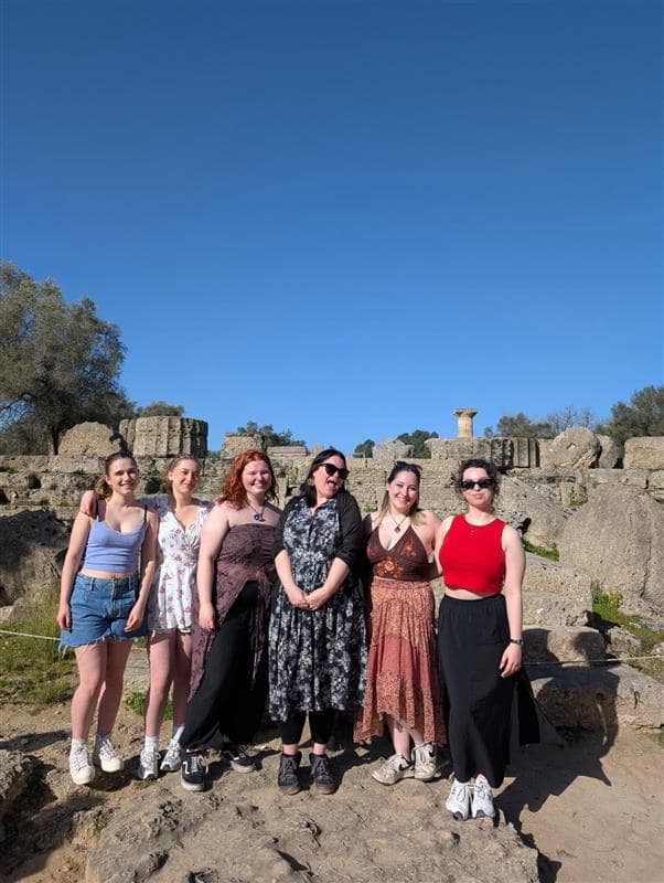 Students and staff smiling for a posed photo in sunshine