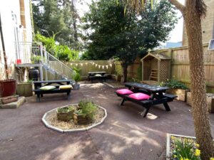 The Huish staff garden on a sunny day, with daffodils, benches with cushions, trees and bunting.