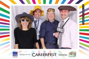 Four staff members with hats on in the photobooth at CareersFest 2024.