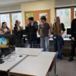Students standing up in a line (in order of their birth months), as part of a careers workshop. Told they couldn't use their voices to form the order, some are holding up numbers on their fingers!