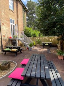 The Huish staff garden on a sunny day, including benches with cushions, trees and bunting.