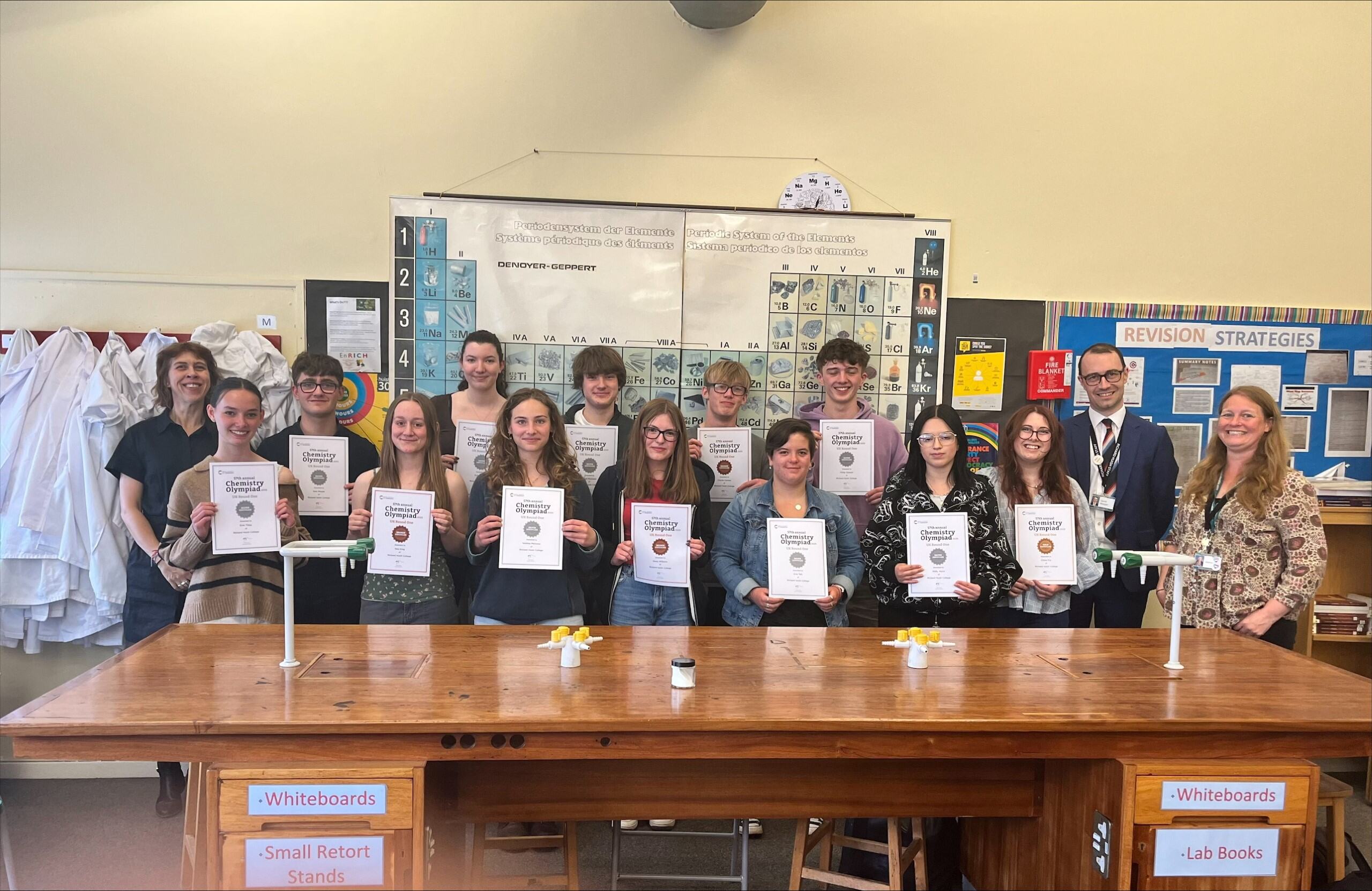 Students in a science lab holding certificates