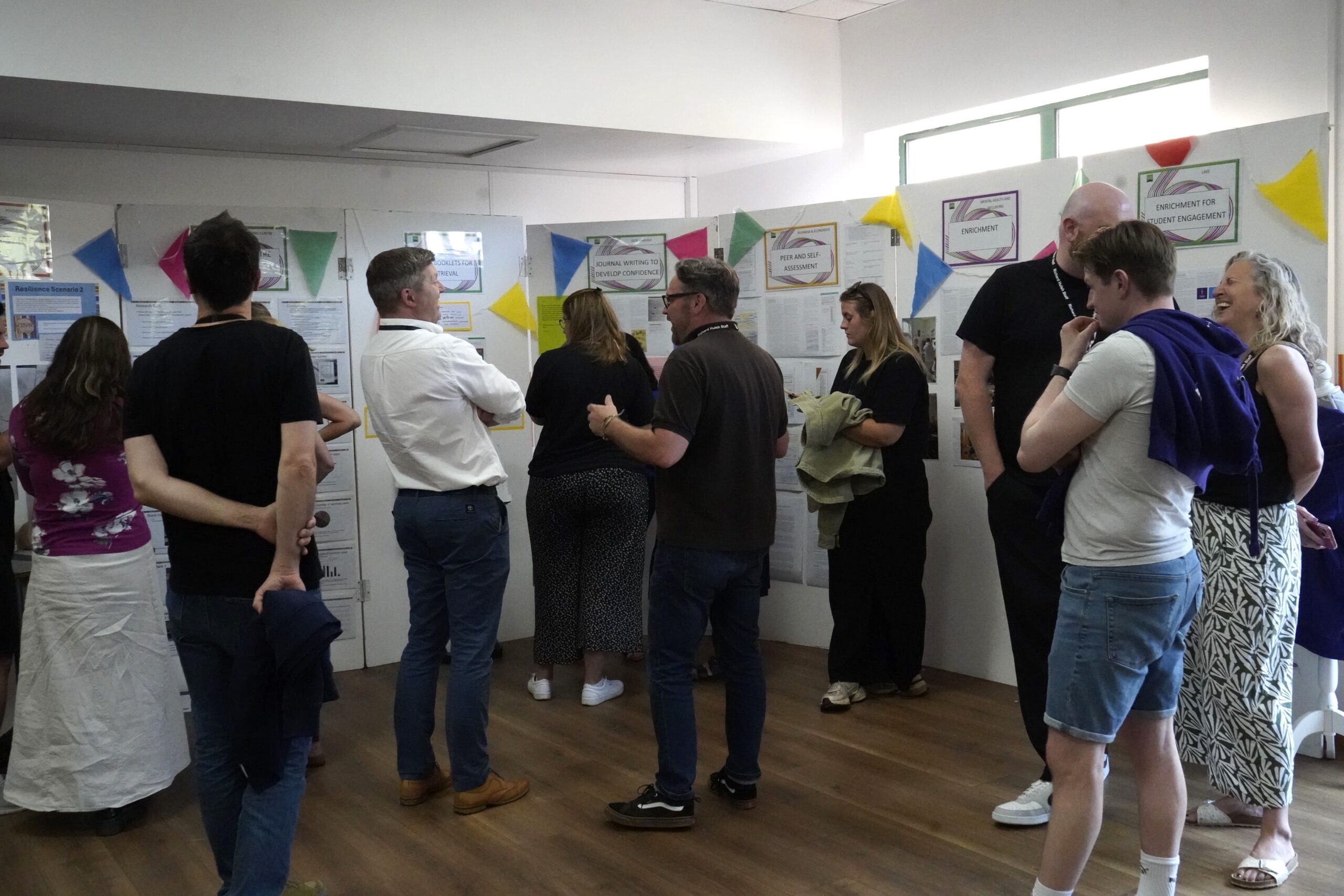Staff in front of stalls at the action research marketplace.