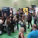 Lots of students chatting to different businesses at the careers fair in the sports hall