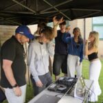Students dance around decks whilst a student and teacher play music on them