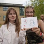 Two students holding up their caricature