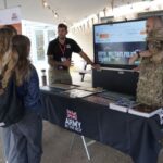 Two army representatives talking to students at an outside stand