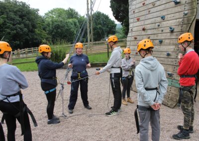 Students preparing for a climbing wall outdoors in safety kit