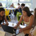 3 students working on their idea around a laptop.