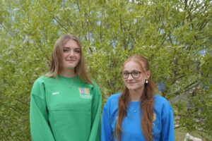 Two student governors stood with one another by a tree