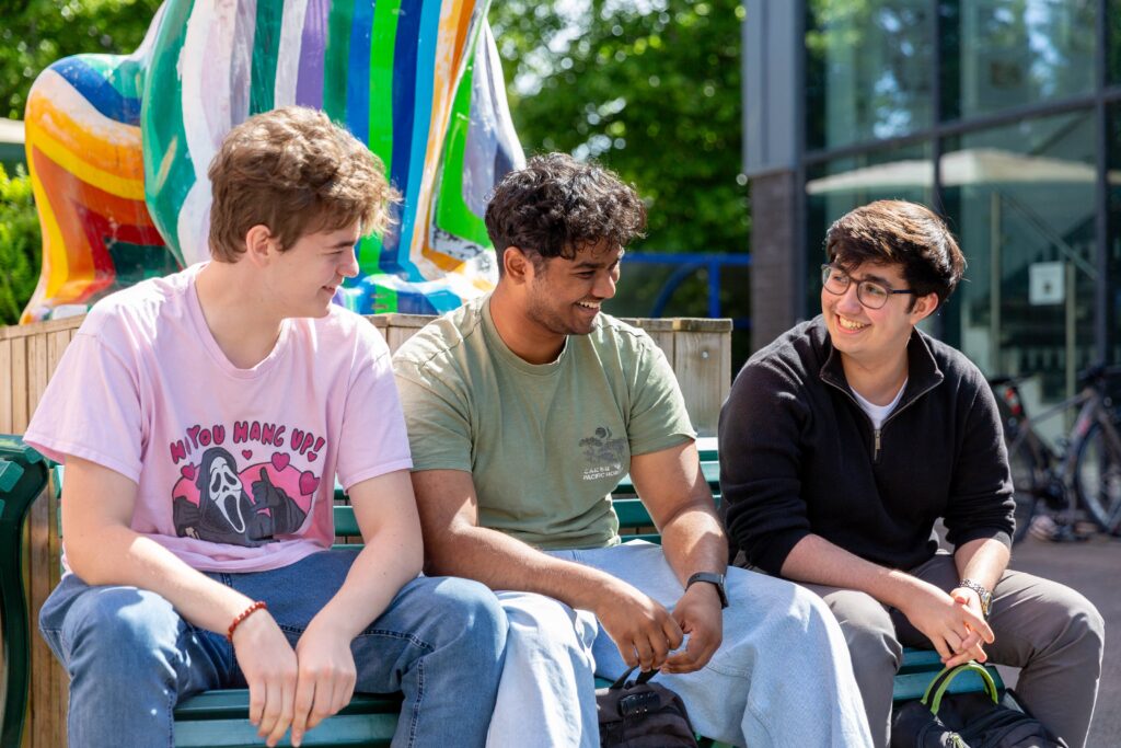 Three students sat by a painted toad statue
