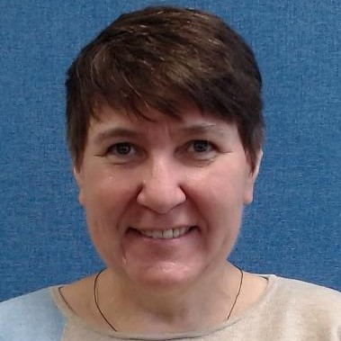 A lady smiling in front of a blue background.