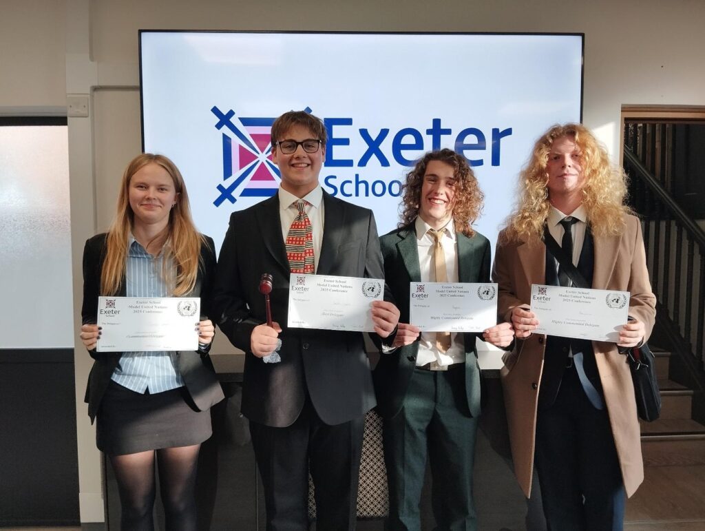 Four students from Huish's MUN programme, dressed smartly and holding up certificates