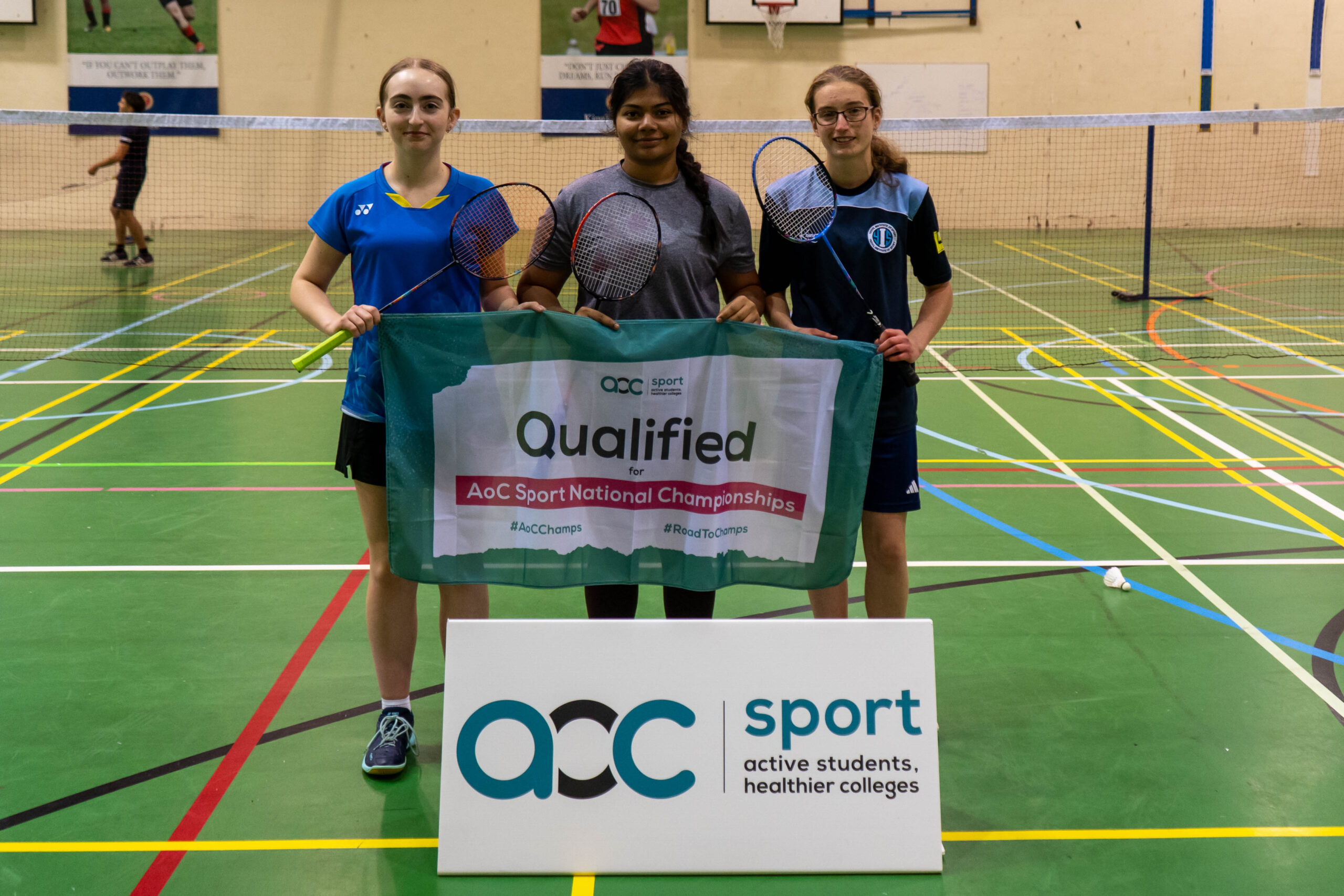 Female Badminton team holding AOC banner