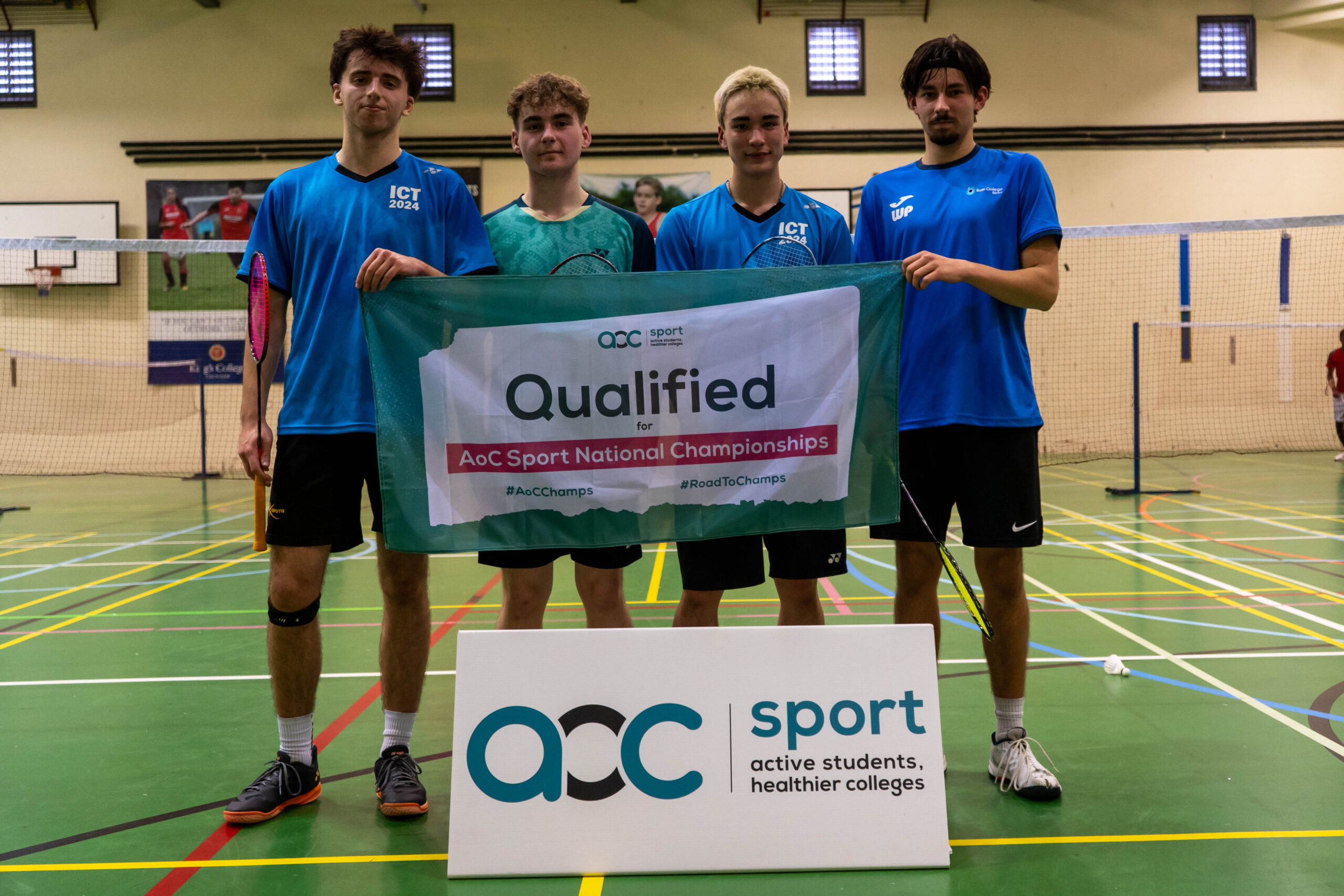 Male Badminton team holding AOC banner
