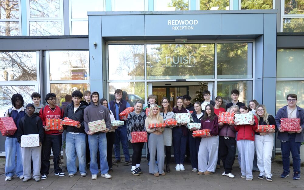 Students and staff standing outside of the front of Huish holding presents wrapped for the Help Thy Neighbour appeal.