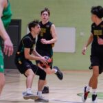 Basketball players from Bush High School in action during a game, with one player dribbling the ball while opponents attempt to defend.