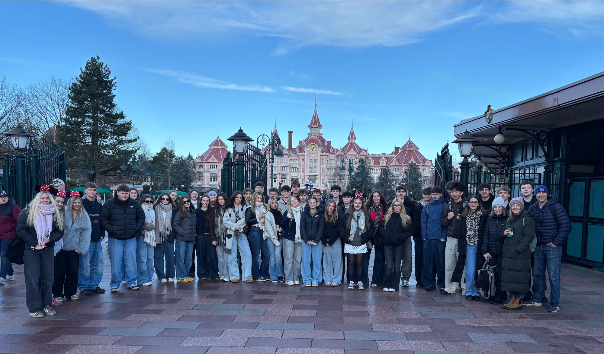 A large group of students on a trip to Disneyland Paris. They are stood in front of an ornate building.