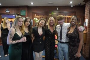 A group of students standing in a row, they are dressed formally.