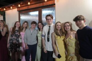 A group of students standing in a row. They are dressed formally and smiling.