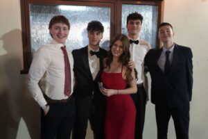 A group of students standing in a row. They are dressed formally and smiling.