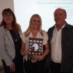 A prize-winning student stands with representatives from Taunton Chamber of Commerce. They are holding the student's trophy and smiling.