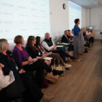Judges sit in a row while a speaker addresses students.