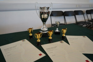 Close-up of trophies and certificates arranged on a green tablecloth.