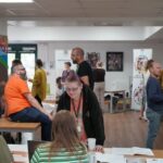 A room full of groups of people chatting next to tables and banners.