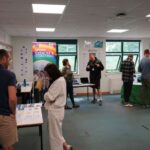 A room full of groups of people chatting next to tables and banners.