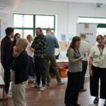 A room full of groups of people chatting next to tables and banners.