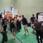 People milling about beside a photobooth. An exhibition stand is in the distance.