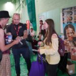 A university or business representative chatting to students at an exhibition stand.