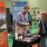 A university or business representative chatting to a student at an exhibition stand.