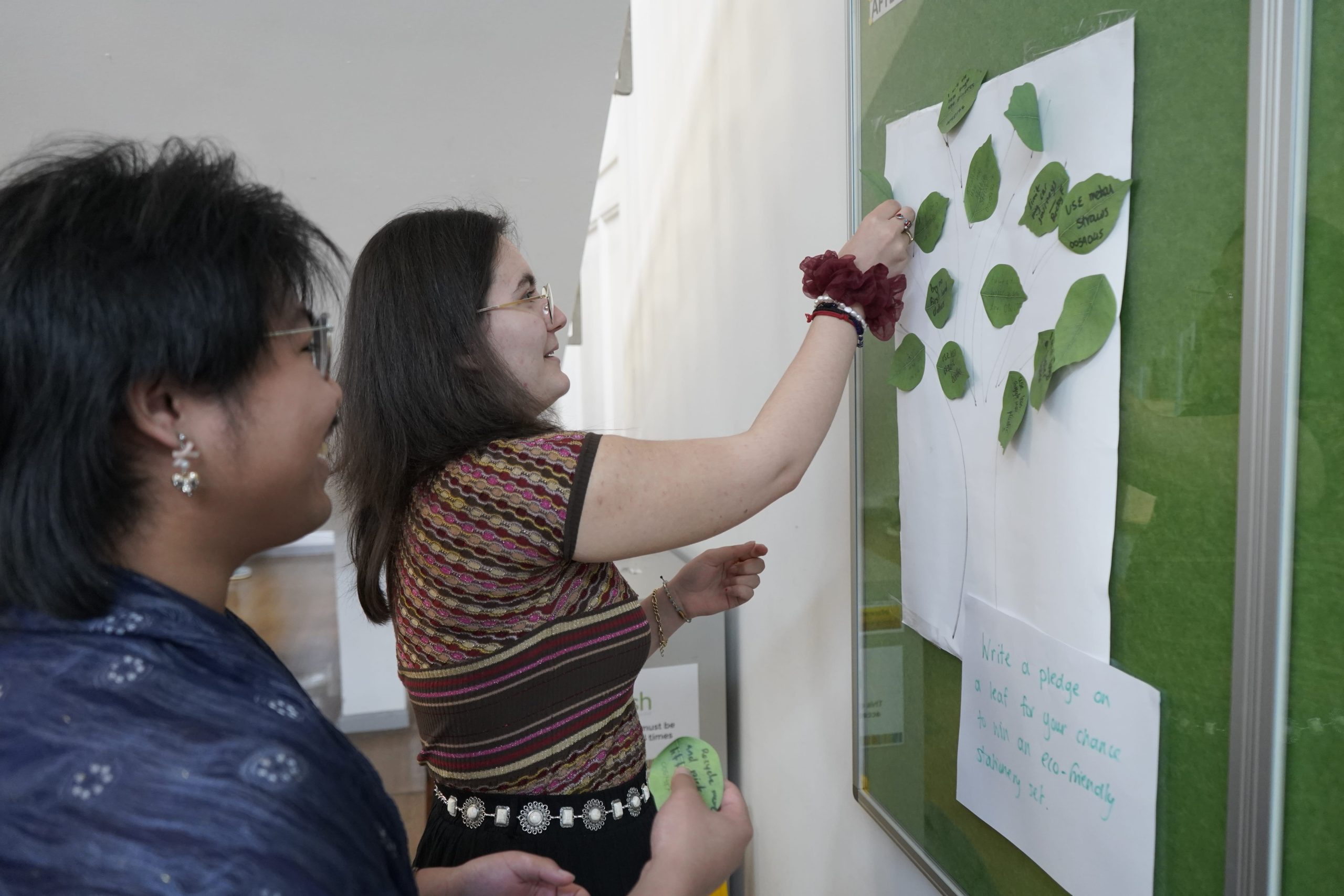 Students sticking paper leaves to wall