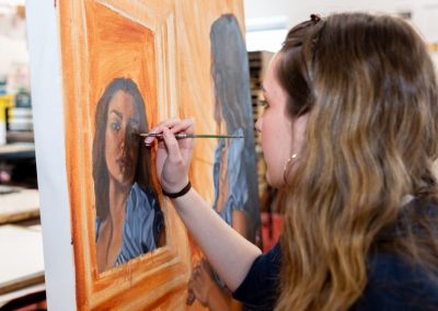 A student working on a painting with a paint brush.