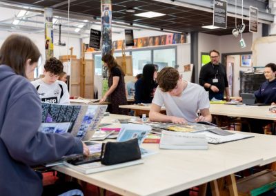 Students work at benches in an art studio.