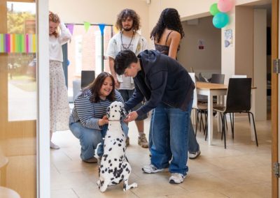 Students interacting with a Dalmatian dog in Oak House’s communal social area, with dining tables, colourful decorations and shared facilities visible in the background.